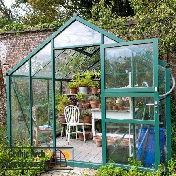 Small greenhouse interior with potted plants and gardening tools